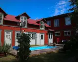 Rött hus med vita fönsterluckor och en blå pool. Kanske finns det tre små rum därinne, redo för gäster.