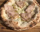 Pizzateig mit Hefe, belegt mit Mortadella und Pistazien. Der Rand ist luftig und leicht angekohlt.