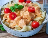 Schmackhafte Nudeln mit Lachs in cremiger Sauce, garniert mit Kirschtomaten und Basilikum. Ein Genuss!