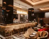 Elegante Bar mit goldenen Akzenten, weißen Barhockern und stilvollen Sitzbereichen. Ein Ort, der zu den besten Restaurants in Berlin passt.