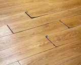 Suelo de madera con tablas levantadas y espacios oscuros, indicando posible daño por humedad. Se busca cómo quitar mancha negra humedad madera.