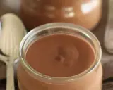 Un pot de crème chocolat onctueuse, prêt à être dégusté avec une cuillère.
