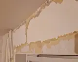 Här ser du hur tapeten flagnar och visar underliggande lager. För att få en slät yta behöver man spackla.