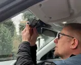 Mężczyzna montuje kamerę samochodową nad lusterkiem wstecznym. Dbałość o szczegóły podczas instalacji zapewnia bezpieczeństwo na drodze.