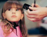 Ein **Kind** bekommt einen neuen **Pony schneiden** im Friseursalon.