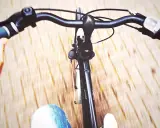 Widok z perspektywy rowerzysty. Dłoń trzyma kierownicę, a przed nami rozmyte tło. Jak podnieść kierownicę w rowerze?