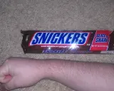 Opakowanie Snickers Slice 'n Share, obok ludzkiej ręki. Zastanawiasz się, snickers ile kalorii?