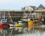 Plusieurs bateaux de pêche colorés sont amarrés dans un port. Une bitte d'amarrage définition : un poteau solide pour attacher les bateaux.