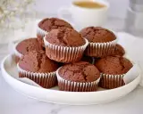 Ein Stapel saftiger Schoko-Muffins, die wie **red velvet muffins** aussehen, auf einem weißen Teller. Im Hintergrund eine Kaffeetasse.