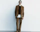 Model in a brown corduroy suit, white shirt, and black sweater, wearing sunglasses.