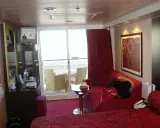 Cabina su MSC Divina, ponte 9, con balcone, divano rosso, letto e quadro astratto.