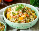 Erfrischender Reissalat mit Mandarinen, Paprika und Kräutern, garniert mit Basilikum.