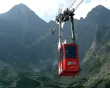 Czerwona kolejka linowa w Tatrach na tle skalistych gór.