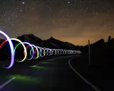 Una carretera nocturna bajo un cielo estrellado, con aros de luz de colores que parecen flotar. ¡Trucos fotos geniales!