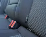 Etiqueta negra con el **símbolo ISOFIX** en el asiento de un coche, junto a los anclajes de seguridad.
