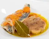 Deliciosa caballa en escabeche con zanahorias, cebolla y laurel en un plato blanco.