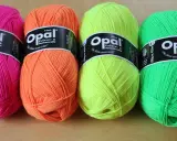 Four balls of Opal yarn in bright pink, orange, yellow, and green.