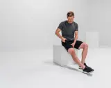 Mann massiert mit Massagepistole seine Oberschenkel, um adduktoren schmerzen zu lindern.