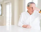 Hombre mayor con expresión de asco se tapa la nariz, sufriendo un olor desagradable en casa sin explicación.