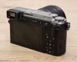 Retro della fotocamera Panasonic Lumix GX80 con obiettivo. Schermo LCD e mirino elettronico visibili.