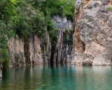 Aguas cristalinas reflejan imponentes rocas y vegetación exuberante en estas piscinas naturales de Castellón. Un rincón idílico para refrescarse.