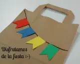 Bolsa de papel decorada con banderines de colores, ideal para hacer bolsas de chuches caseras y disfrutar de la fiesta.