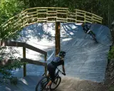 Två cyklister på en träbana i skogen, en spännande mtb-upplevelse nära Stockholm.