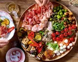 Große Platte mit Antipasti: Wurst, Schinken, Oliven, gegrilltes Gemüse, Tomaten, Mozzarella. Perfekt für Antipasti Rezepte.