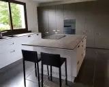 Cuisine moderne avec îlot central. On peut facilement faire le tour de cet îlot central pour accéder aux plans de travail et aux tabourets.