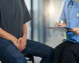 Mężczyzna w dżinsach i szarej koszulce rozmawia z lekarką, która notuje na kartce. Czy zapalenie prostaty przechodzi samo?