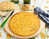 Una gustosa farinata di ceci in padella, pronta per essere gustata con pane fresco e un rametto di rosmarino.