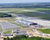 Lotnisko Warszawa Modlin z lotu ptaka: nowoczesny terminal, pas startowy i rozległe tereny zielone.