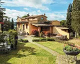 Un perfetto weekend in Toscana: villa con giardino fiorito, cipressi e un cielo azzurro con nuvole bianche.
