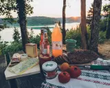 Pique-nique avec fromages, pain de campagne, jus de poire et terrine, un aperçu des spécialités culinaires Jura au bord d'un lac.