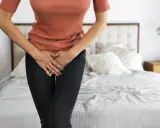 Mujer con las manos en el abdomen, sintiendo dolor de ovarios y gases.