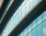Fachada de edificio moderno con paneles de cristal azul que reflejan el cielo. El **solar glass** captura la luz del sol para generar energía.