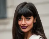 Frau mit leichter Pony und langen, dunklen Haaren, auffälligem Make-up und dunklem Lippenstift.
