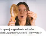 Zaskoczona kobieta trzyma szczotkę z garścią wypadających włosów. Dowiedz się, jak wzmocnić wypadające włosy i co wybrać: tabletki, szampony czy wcierki.