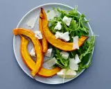 En härlig sallad med ruccola och fetaost, toppad med ugnsrostad pumpa och en citronskiva.