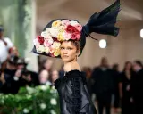 Zendaya stuns at the Met Gala in a dramatic black gown and a voluminous hat adorned with a cascade of colorful roses.