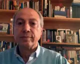 Carmine Abate, con libreria alle spalle, parla in videochiamata.