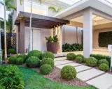 Vialetti giardino moderni con siepi sferiche e un pergolato in legno creano un percorso accogliente verso la casa.