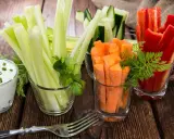 Geschnittene Karotten, Sellerie, Gurken und Paprika in Gläsern, dazu ein Dip. Perfekte Snacks nach dem Sport für gesunde Erholung.