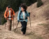 Para dobrać kije trekkingowe do wzrostu, zwróć uwagę na kąt 90 stopni w łokciu podczas marszu. Para turystów z kijkami na górskim szlaku.