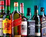 Eine Reihe von Whiskyflaschen, darunter Johnnie Walker Red Label, Jack Daniel's und Chivas Regal. Die Frage "wie viel prozent hat whisky" wird durch die 40% Vol. auf der Jack Daniel's Flasche beantwortet.