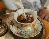Té floral servido en una taza decorada, perfecto para celebrar los 20 años de casados. Un detalle de joyas antiguas añade elegancia.