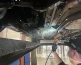 Profesjonalne zabezpieczenie antykorozyjne podwozia samochodu. Mechanik aplikuje preparat ochronny.