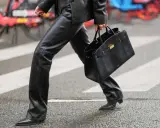 A person walks across a crosswalk in a chic leather pants outfit, perfect for winter. They carry a stylish black handbag.