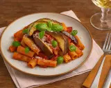 Pasta alla Norma mit Auberginen, Tomatensauce und Basilikum auf einem Teller, garniert mit Parmesan.