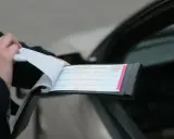Policjant wypisuje mandat. Na dokumencie widnieje numer 1934776. Nie wiadomo, ile jest pkt karnych.
